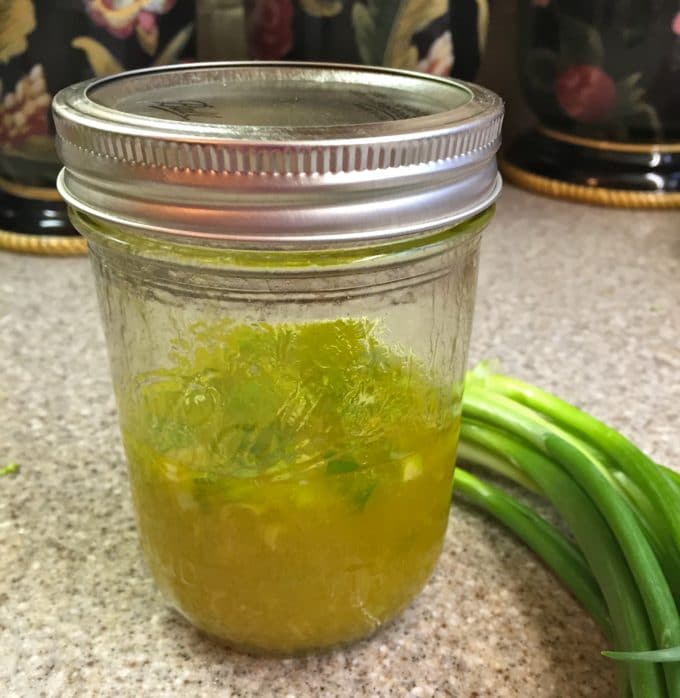 A small mason jar filled with vinaigrette for Potato Broccoli Salad with Vinaigrette