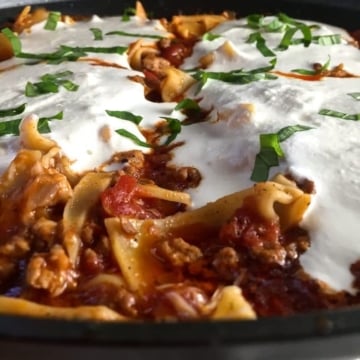 Skillet lasagna in a pan with melted ricotta cheese.