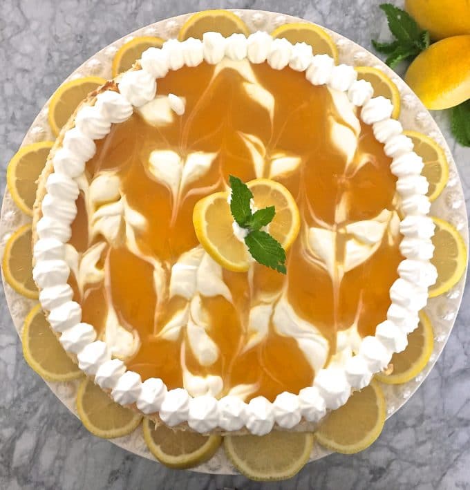 A cheesecake with lemon swirls topped with piped whipped cream. 