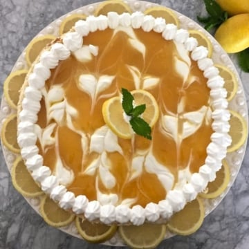 Lemon Swirl Cheesecake garnished with mint and lemon slices on a white plate.