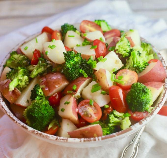 Cooked New Potatoes, broccoli and cherry tomatoes in a white serving bowl for Potato Broccoli Salad with Vinaigrette