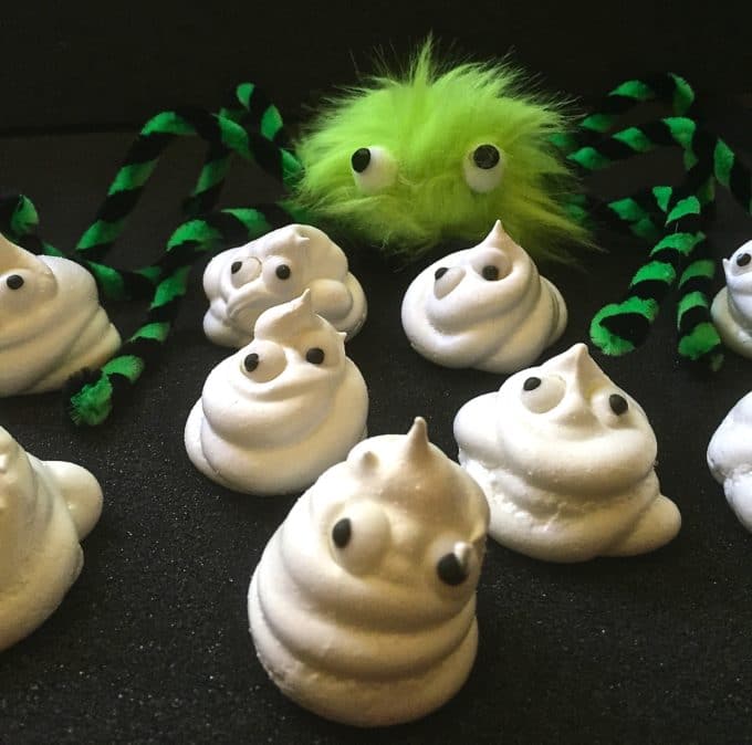 Easy Halloween Ghosts made with meringue and googly eyes. A green furry spider lurks in the background. 