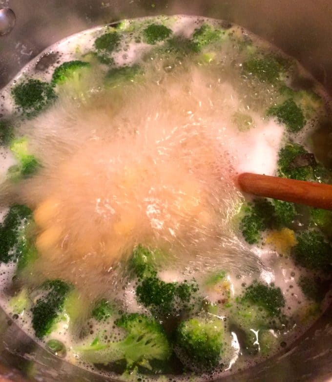 Cooking the pasta and broccoli in a large pot of boiling water for Slow Cooker Chicken Broccoli Pasta