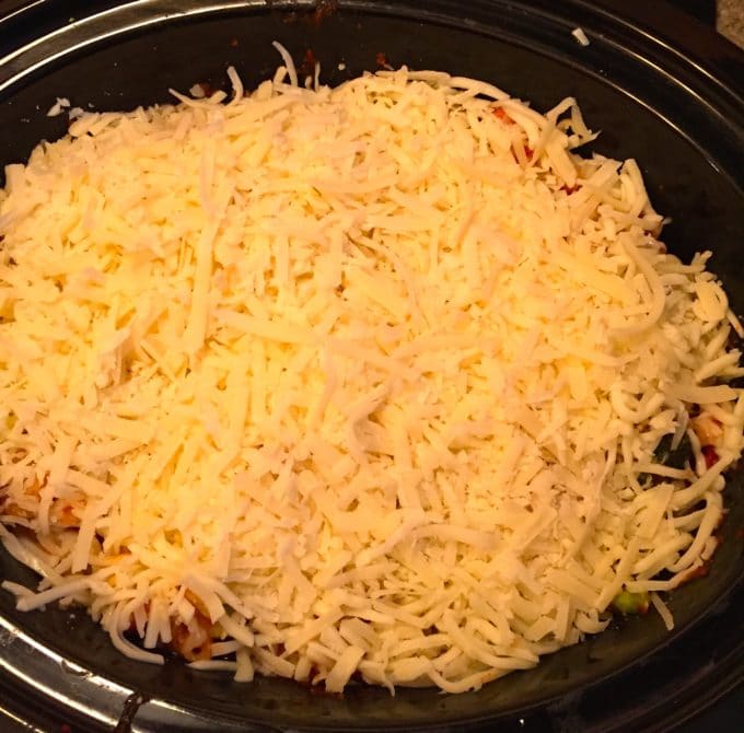 Topping Slow Cooker Chicken Broccoli Pasta with cheddar and parmesan cheeses 