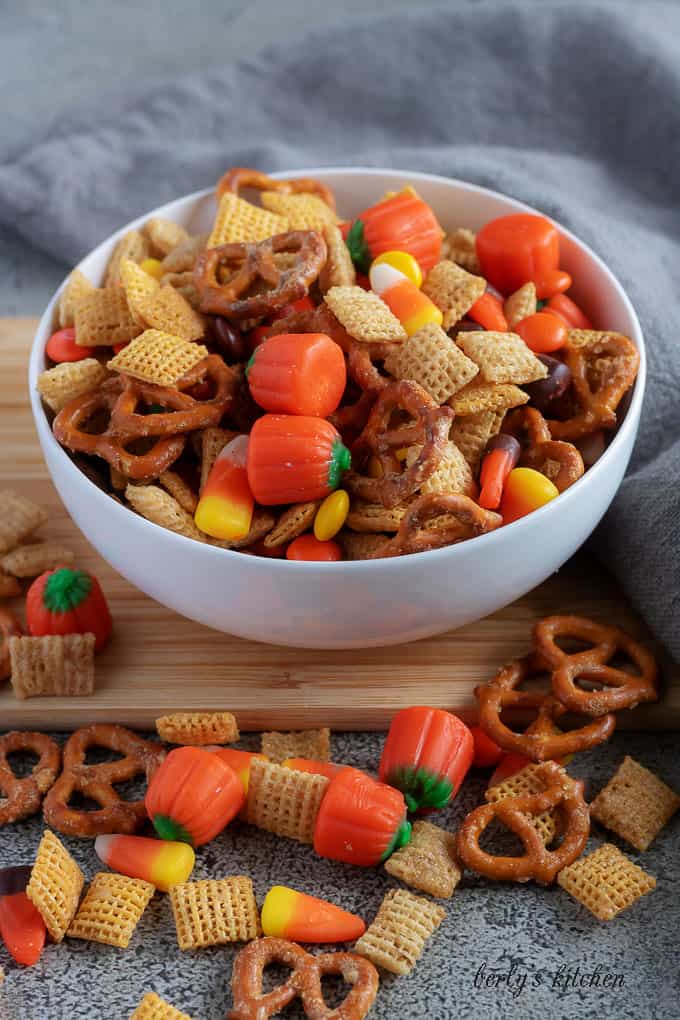 Halloween party mix in a white bowl with pretzels and candy pumpkins.