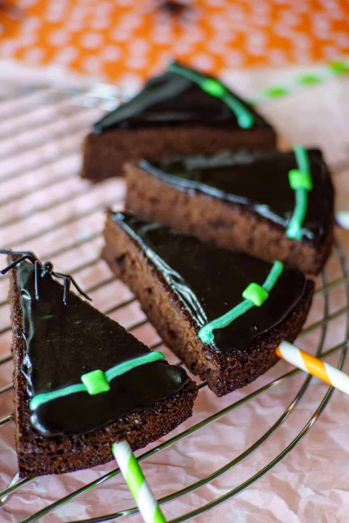 Brownie pops cut into the shape of a witches hat and covered with chocolate frosting.