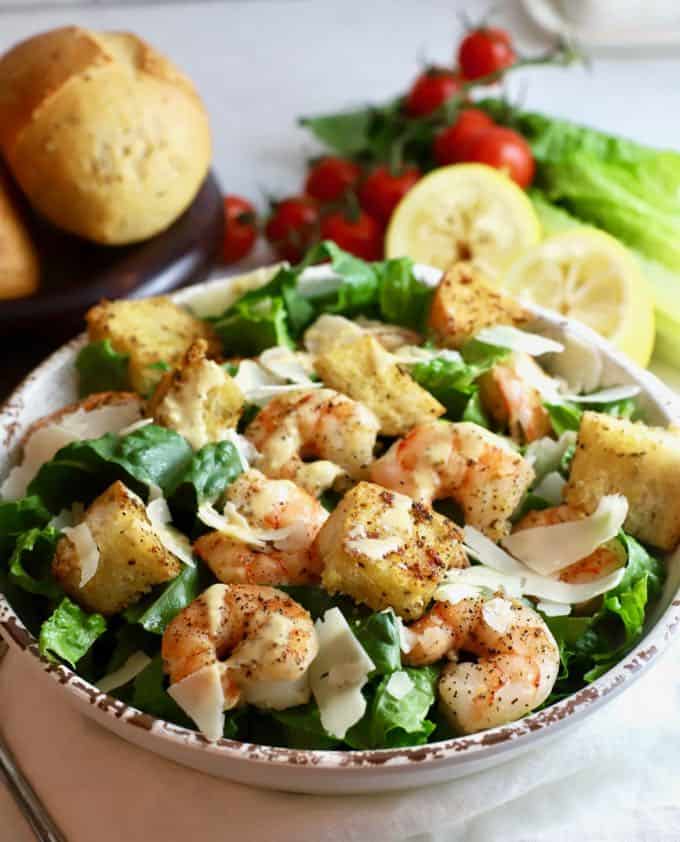 A white bowl full of Shrimp Caesar Salad with homemade croutons and dressing.