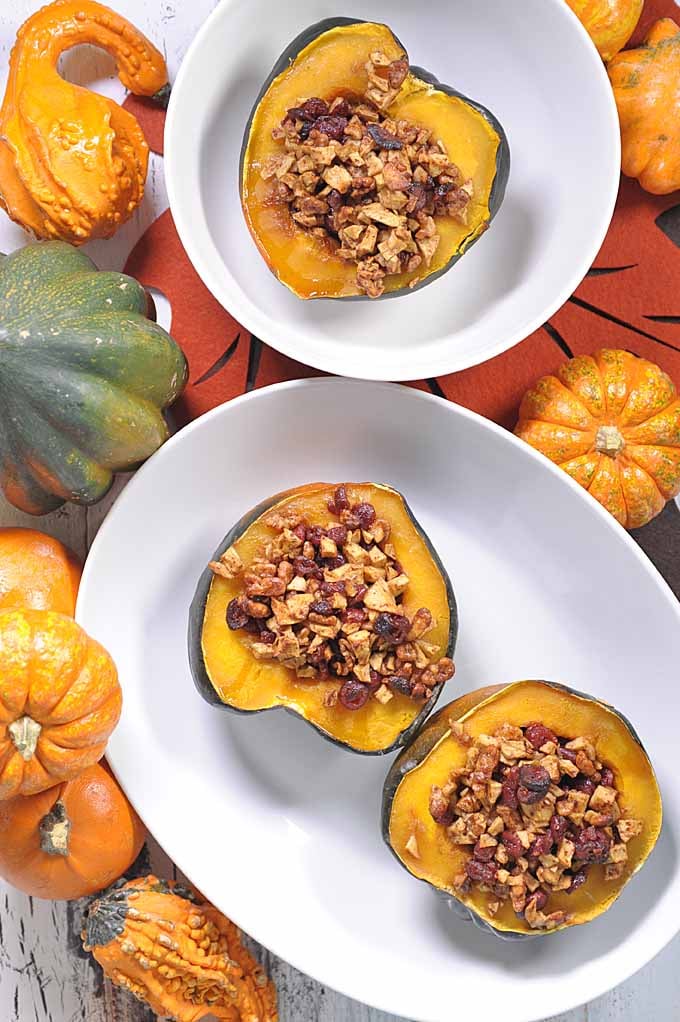 Cranberry and walnut stuffed acorn squash on a white plate.