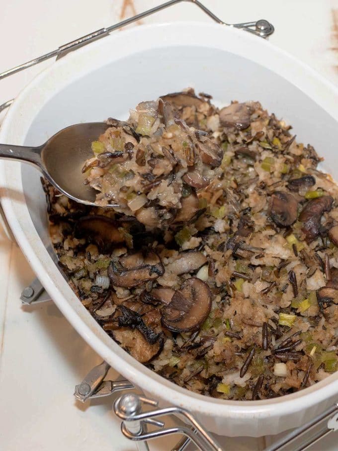 Mushroom Wild Rice Stuffing in a white corning baking dish on a metal stand. 