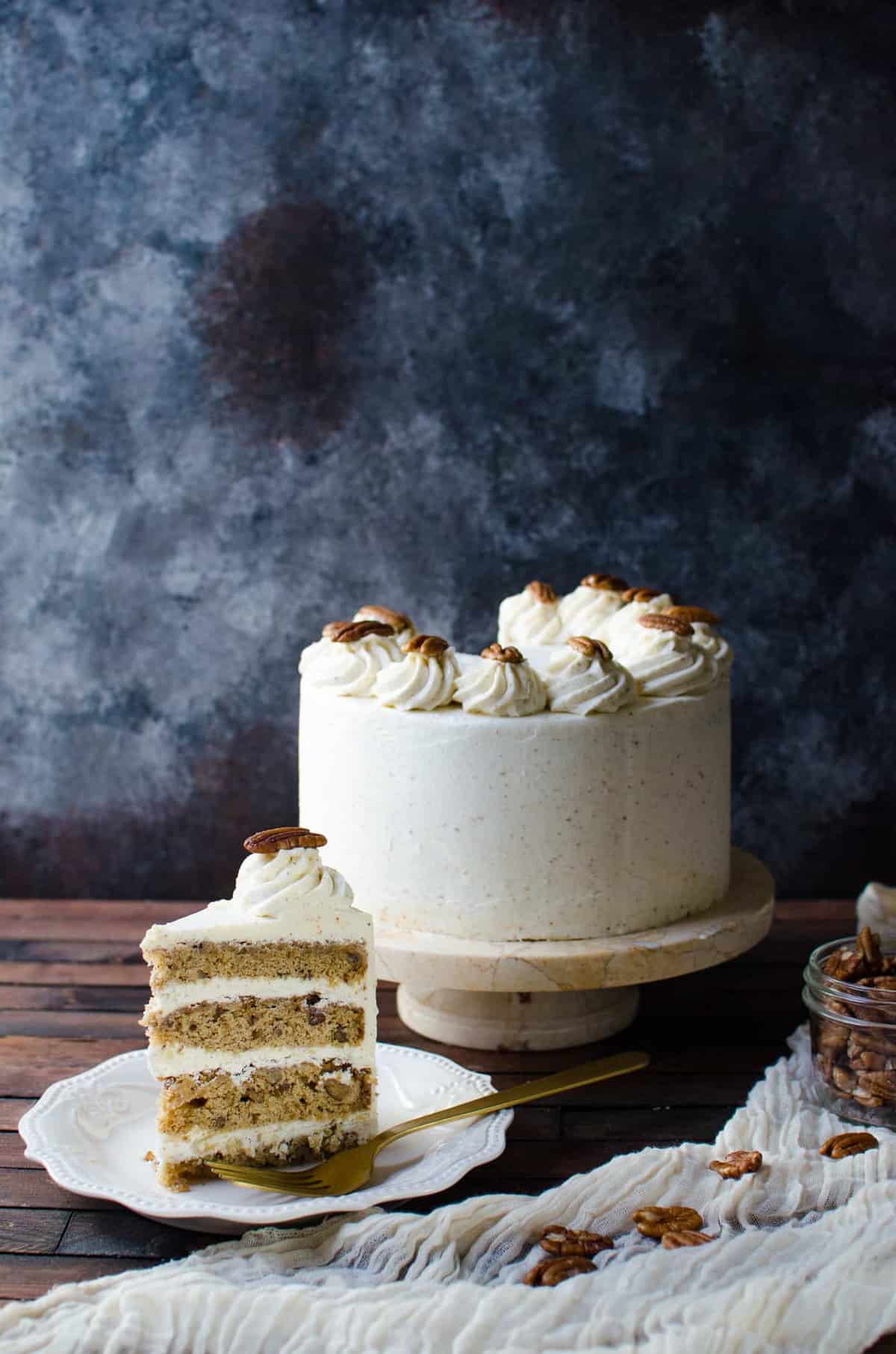 A whole pecan cake with butter icing with a slice cut out.