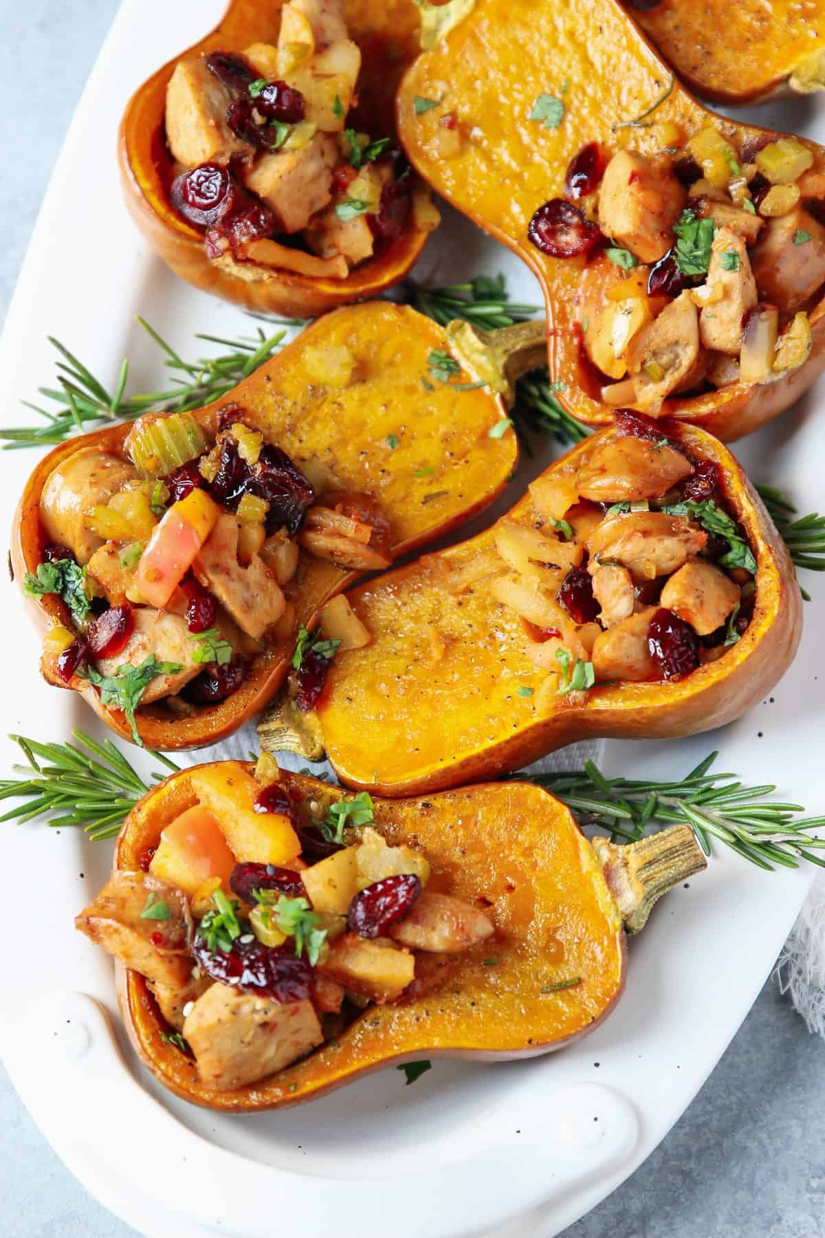 Five sausage and apples stuffed Honeynut squash on a plate. squaSH