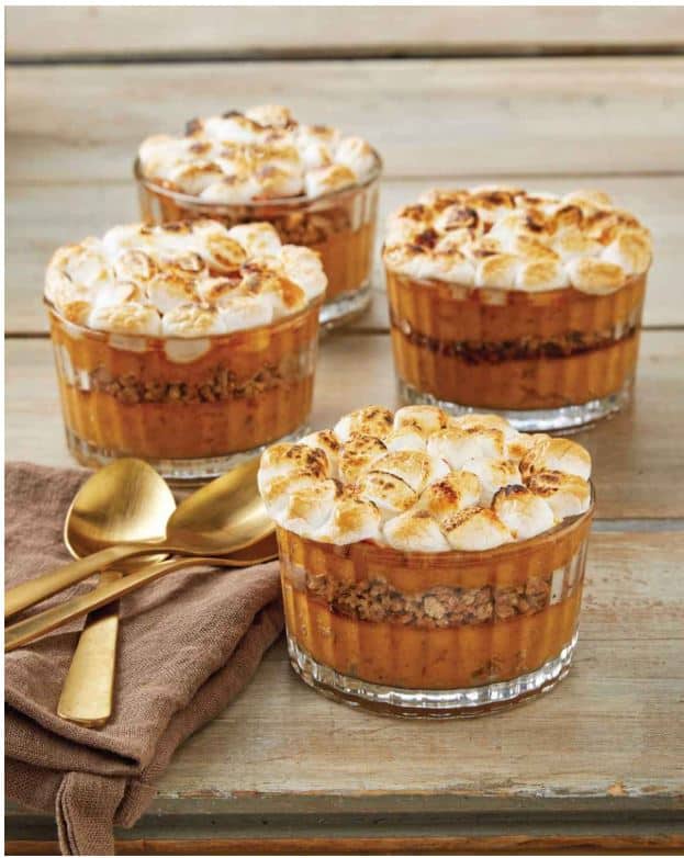 Four individual sweet potato casseroles topped with marshmallows in clear glass dishes