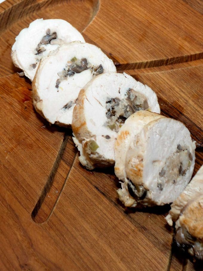 Turkey roulade cut into slices on wooden cutting board.