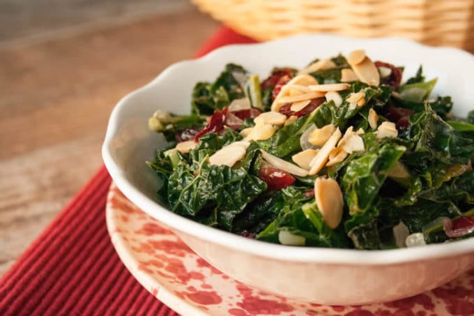 Thanksgiving Kale in a white glass bowl topped with chopped almonds.