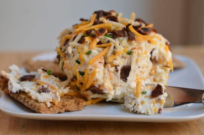 Low fat bacon cheeseball on a plate with crackers and a knife. 