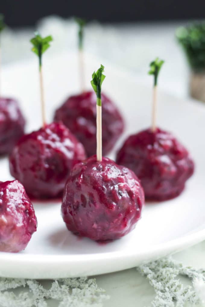 Cranberry sage meatballs with cocktail picks on a white plate. 