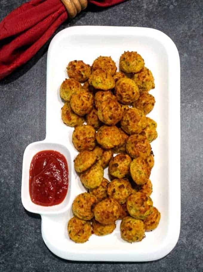 Easy cheesy zucchini bites on a white plate with catsup. 