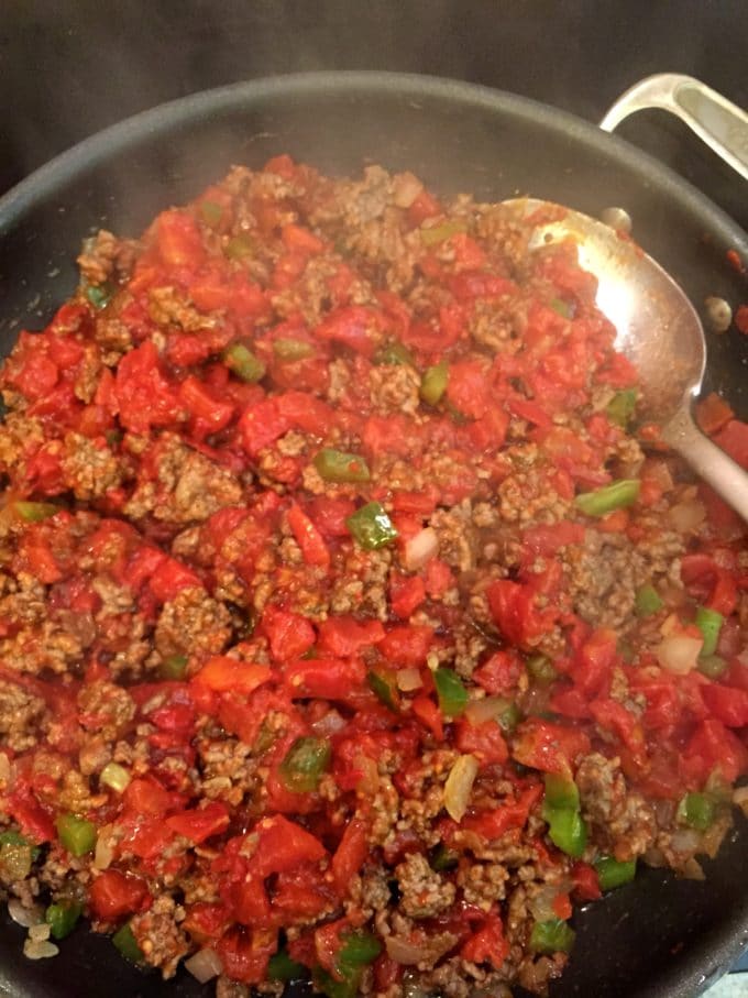 Adding tomatoes to the cooked beef mixture for Beef and Tomato Skillet with Polenta