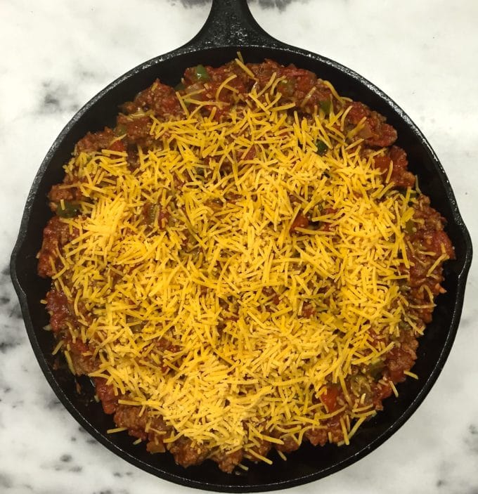 Adding a cheese topping to Beef and Tomato Skillet with Polenta before it is baked