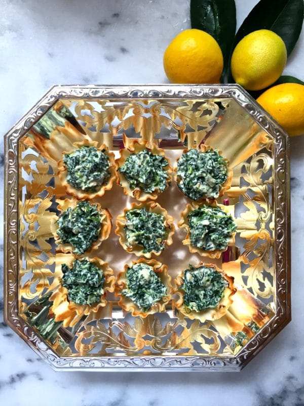 Nine Spinach and Goat Cheese Tartlets in a serving tray with lemons in background.