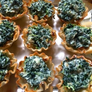 Nine Spinach and Goat Cheese Tartlets on a white cloth.