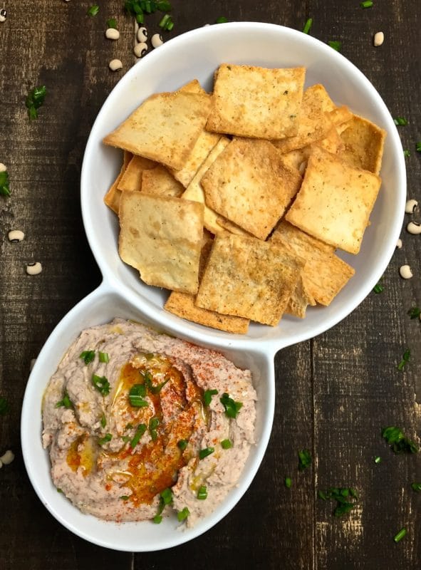 Black-Eyed Pea Hummus and pita chips in white duo bowl.