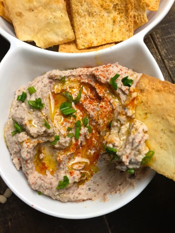 Black-Eyed Pea Hummus and pita chips in white duo bowl.