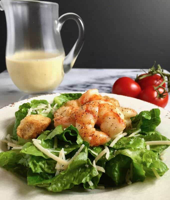 Caesar salad with roasted shrimp on a white plate. 