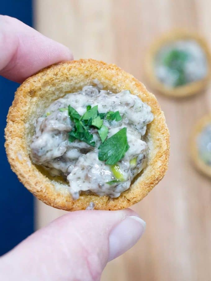 Mushroom croustades appetizer topped with chopped parsley. 