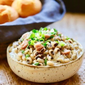 Southern Hoppin' John in a bowl with corn muffins in a basket in the background.