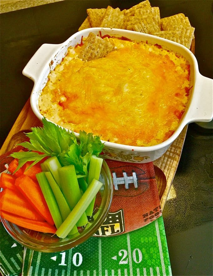 Buffalo Chicken Dip in a white baking dish with carrots and celery and game day napkins.