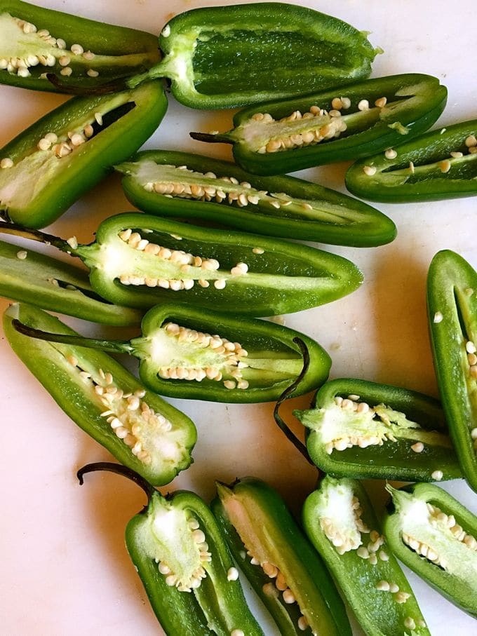 Jalapeño peppers cut in half showing the seeds and ribs. 
