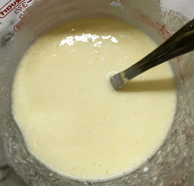 Mixing eggs, buttermilk, and oil together in a large glass measuring cup.