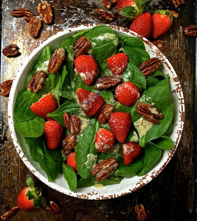 Spinach Salad with Strawberries and Pecans in a white bowl with poppy seed dressing.