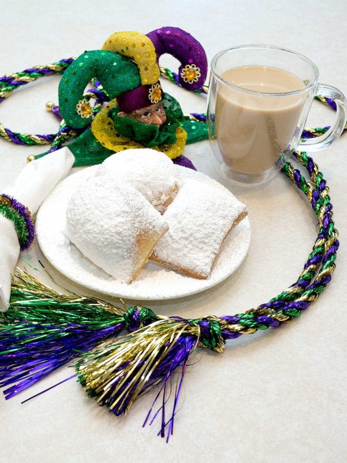 Three beignets topped with powdered sugar on a plate. 