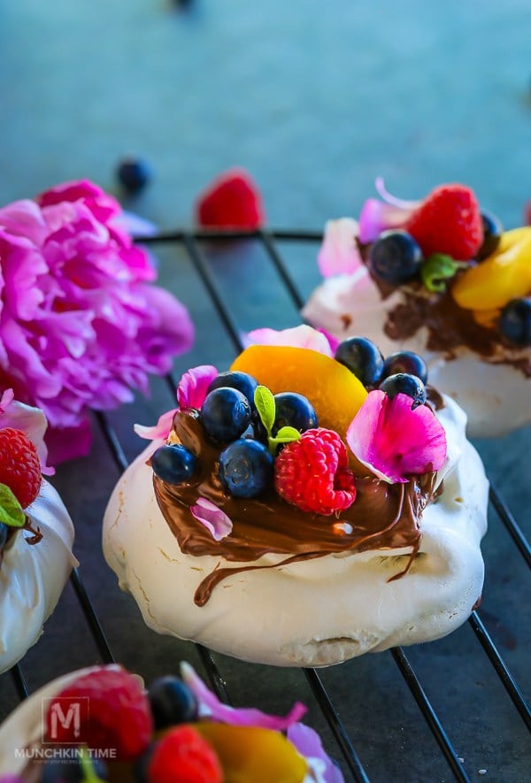 A pavlova filled with peach slices, raspberries and blueberries. 