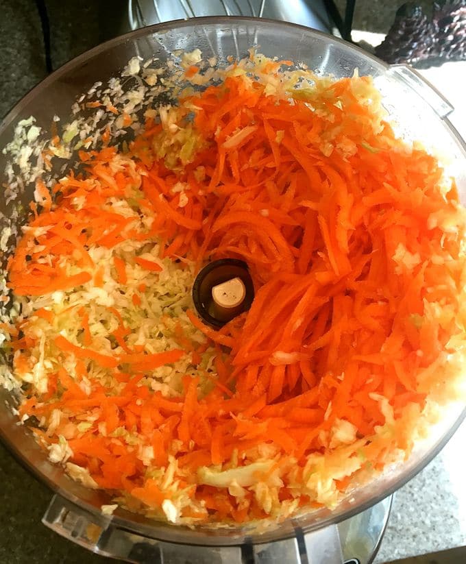 Shredding cabbage and carrots in a food processor for Corned-Beef-and-Cabbage-Egg-Rolls.
