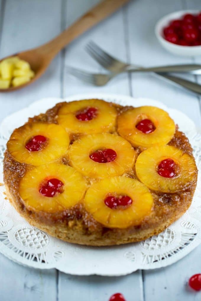 A whole pineapple upside down cake topped with pineapple rings and cherries. 
