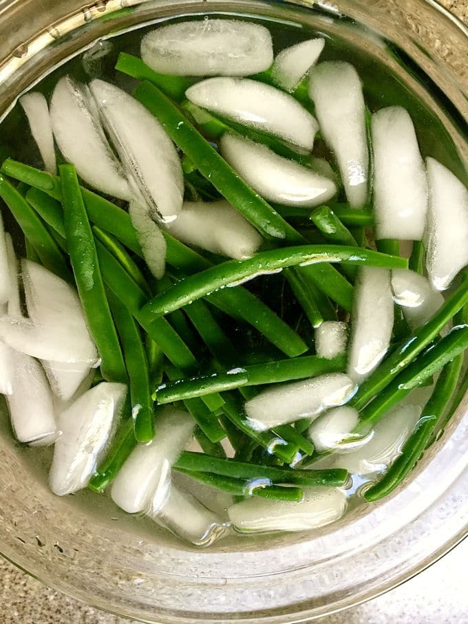 Green beans in large bowl of ice water.