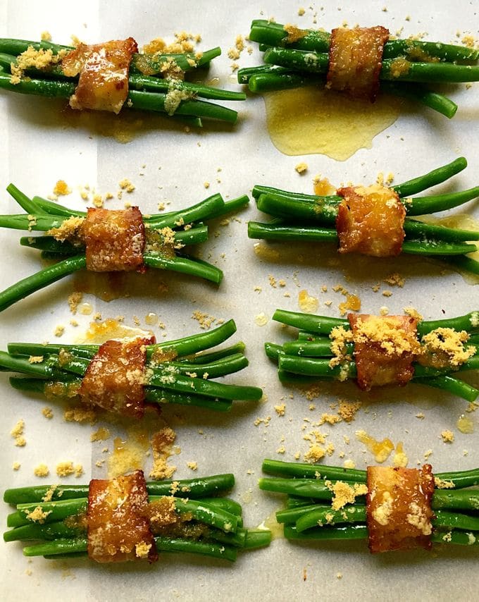 Green Bean Bundles Wrapped in Bacon with brown sugar and butter topping on a baking sheet ready for the oven.