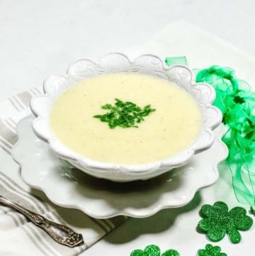 A bowl of potato soup garnished with chopped parsley.