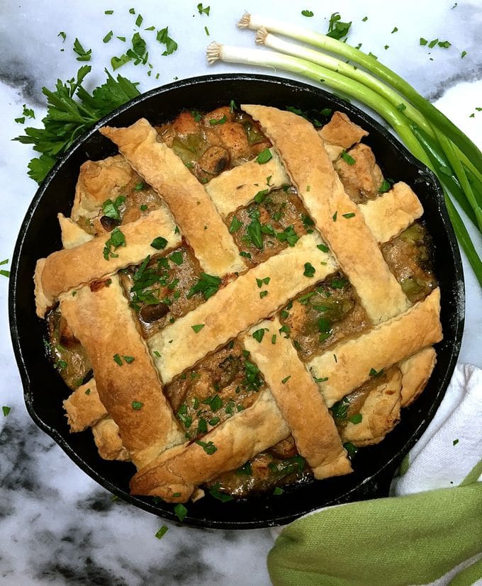 Chicken pot pie with lattice pastry garnished with parsley.