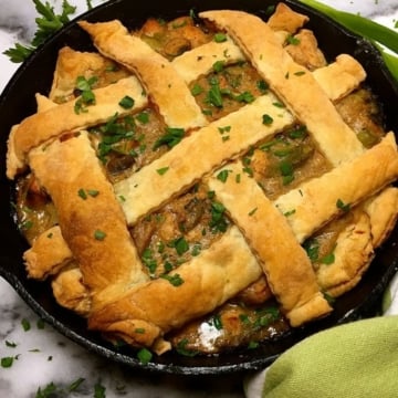 Chicken pot pie with lattice pastry garnished with parsley.