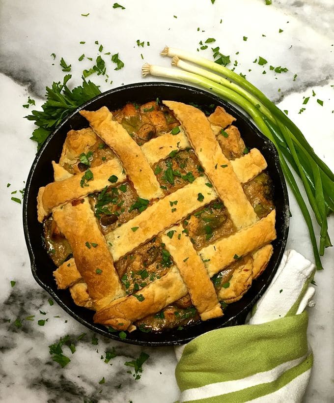 Chicken pot pie with lattice pastry garnished with parsley.