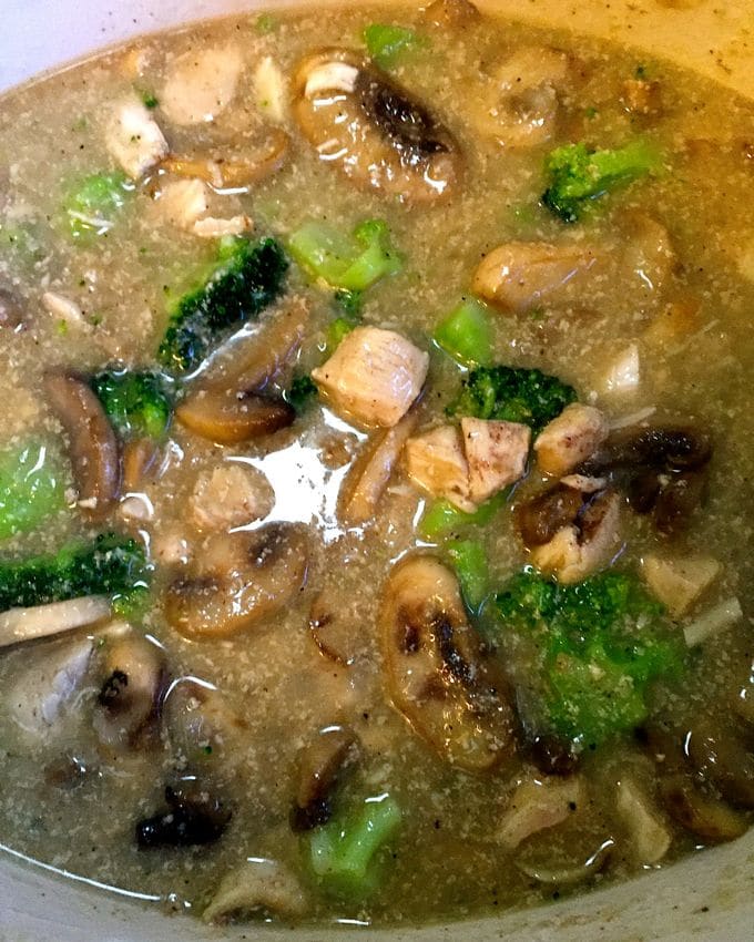 Chicken, broccoli, and mushrooms in a pan with chicken stock.