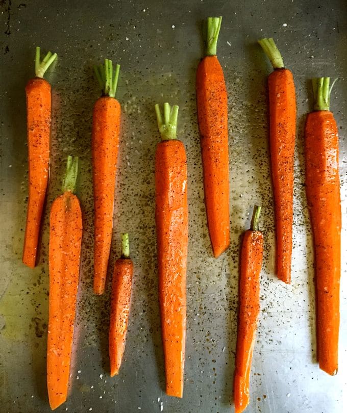 Carrots sprinkled with salt and pepper on a baking sheet.