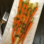 Roasted Carrots with Lemon Vinaigrette garnished with parsley on a white serving platter.