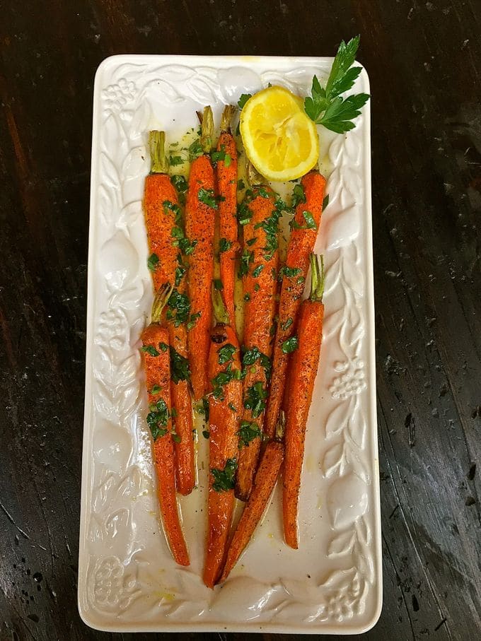 Roasted Carrots with Lemon Vinaigrette garnished with parsley on a white serving platter.