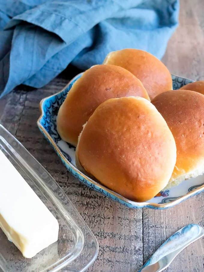Amish Potato Rolls on the table with butter and a blue napkin.