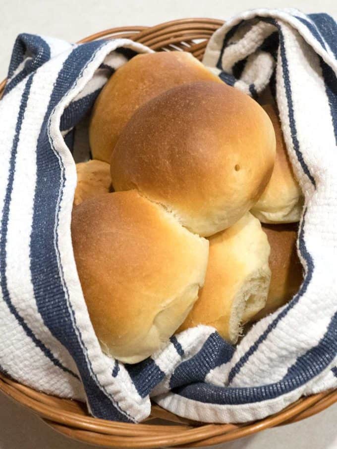 Buttery Dinner Rolls in a basket with blue and white napkin. 